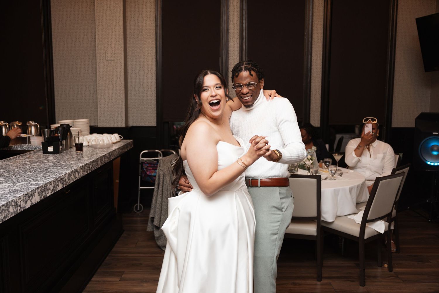 Joyful bride and groom dancing together at their wedding reception in an elegant banquet hall.