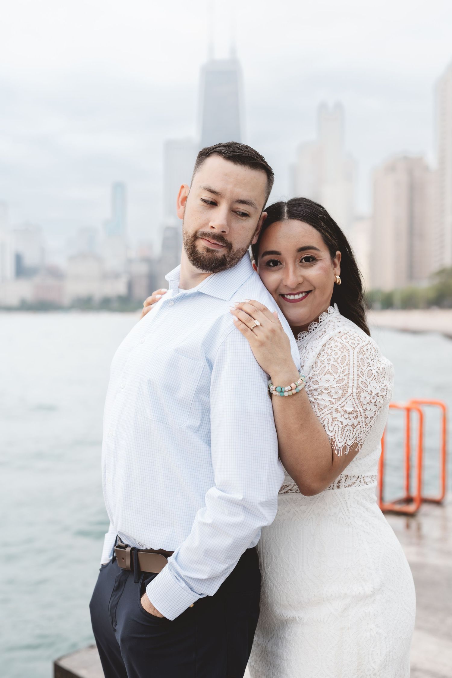 Smiling bride leaning on groom with Chicago skyline and lake visible in background.