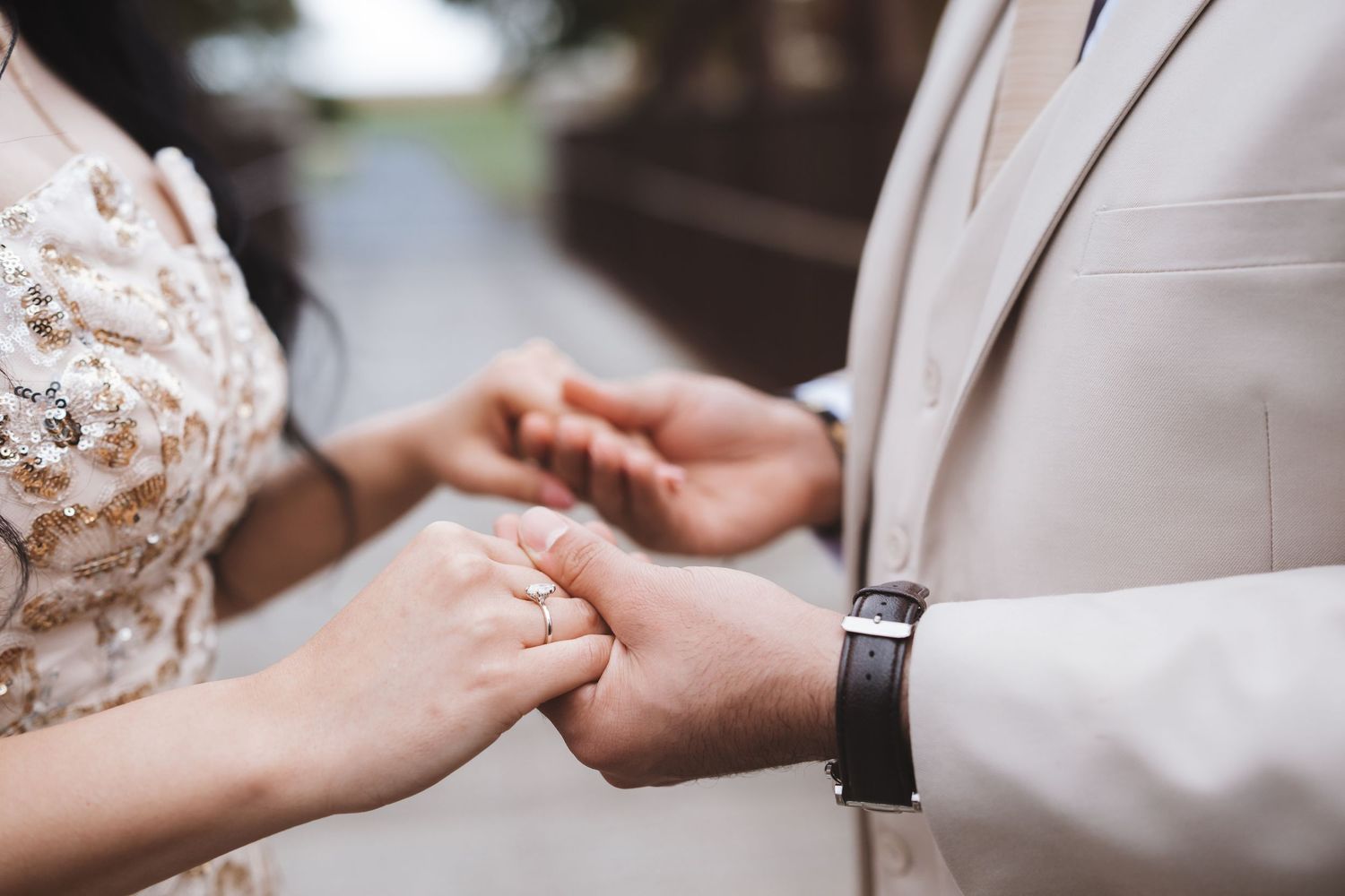 Close-up of bride and groom exchanging rings, highlighting the wedding band and elegant lace bridal gown detail.