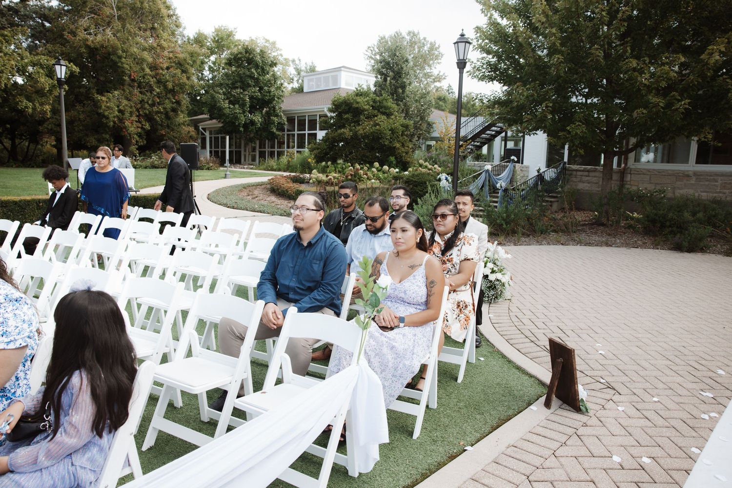 Guests seated in white chairs at an elegant outdoor wedding ceremony venue.