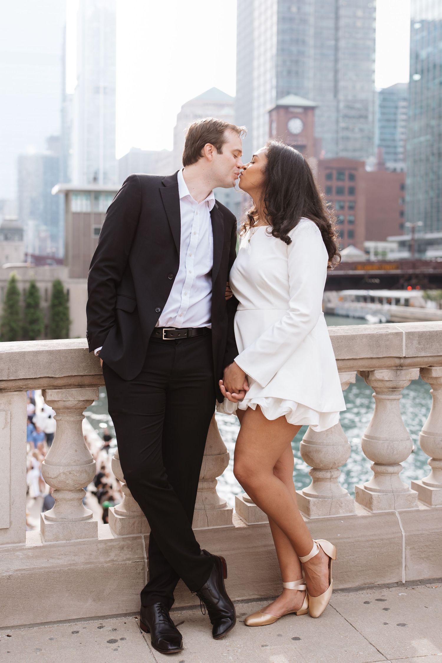 Couple kissing on a Chicago bridge terrace with city skyline and river in background.