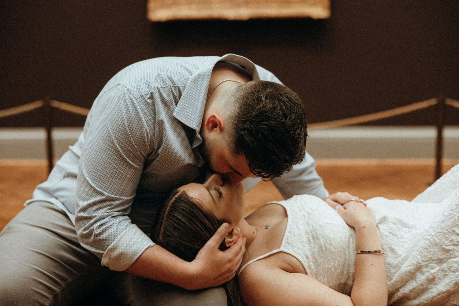 Romantic couple sharing a tender kiss, man leaning over woman lying down in an intimate embrace.