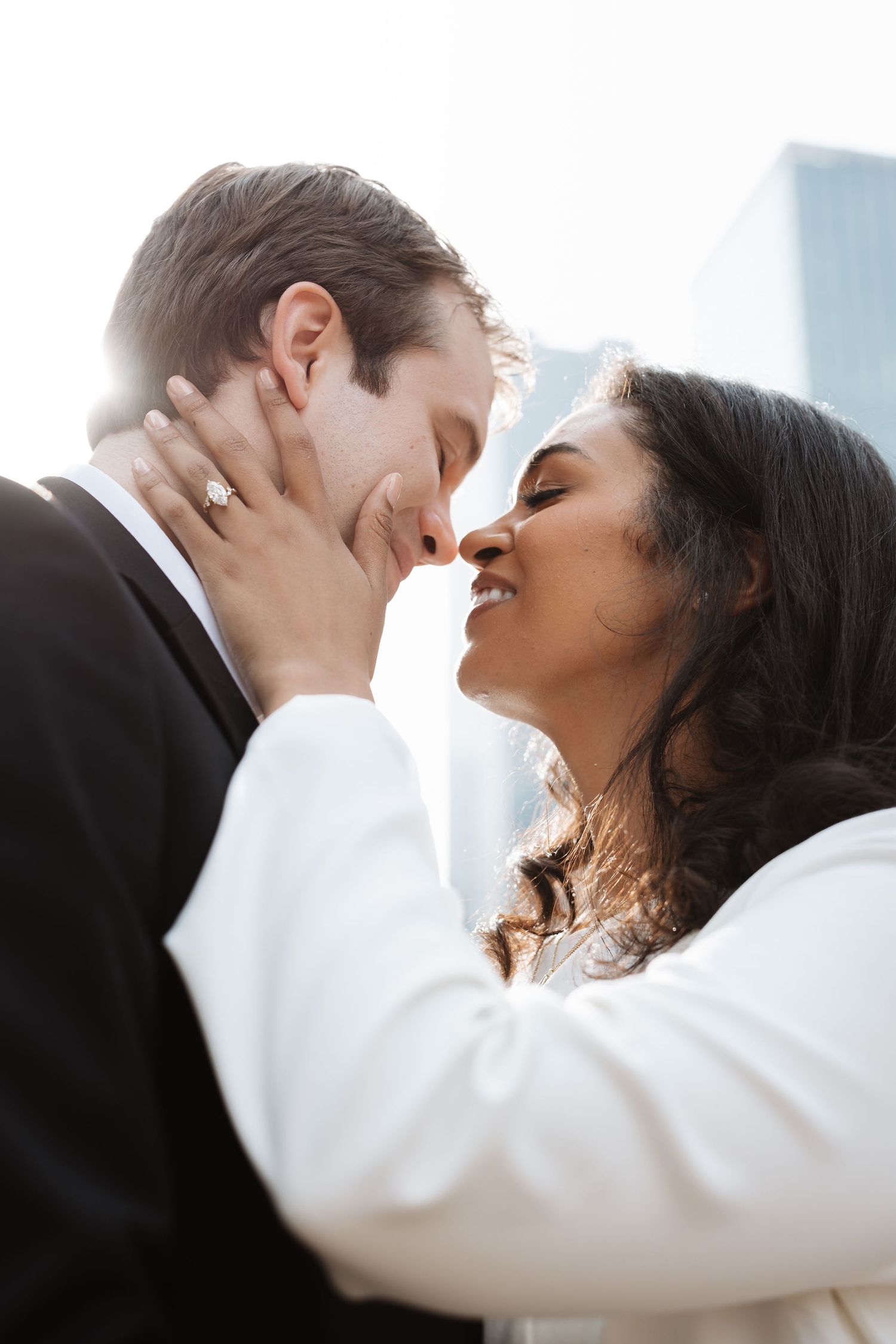 Interracial couple sharing a romantic kiss with Chicago skyscrapers glowing in the background.