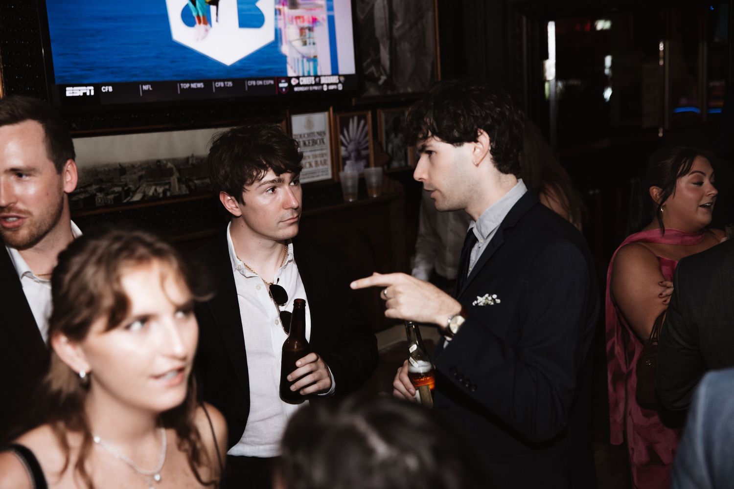 Guests in formal attire socializing at an indoor wedding reception bar event.