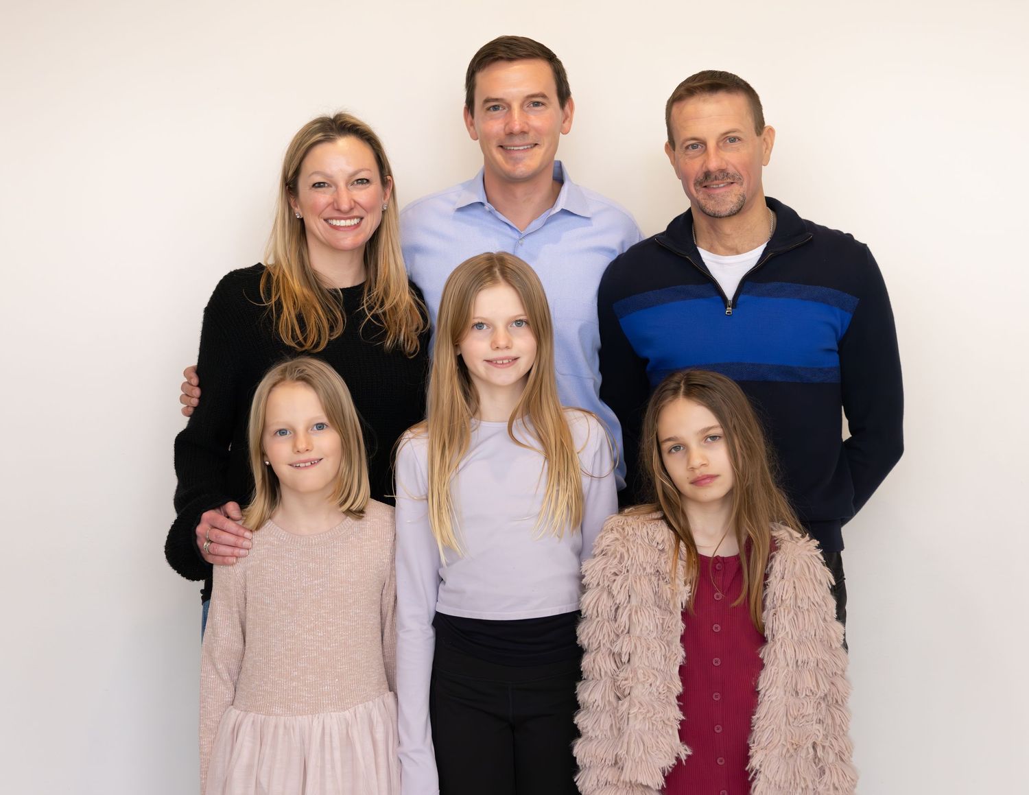A happy family of six poses together for a formal portrait against a white background.