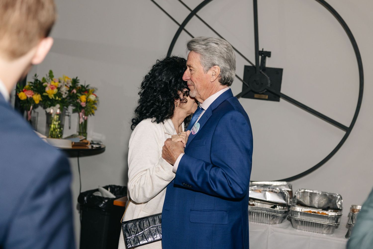 Older couple sharing a warm dance together at a wedding reception in a modern venue.