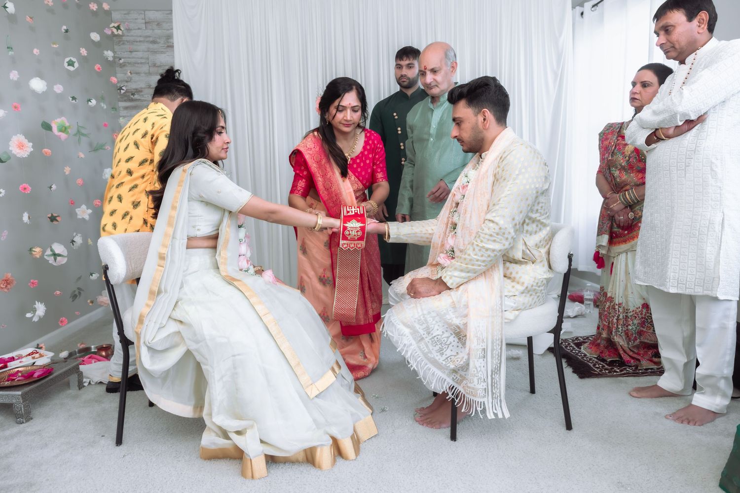 Indian wedding ritual with bride and groom joining hands surrounded by family in colorful traditional attire.