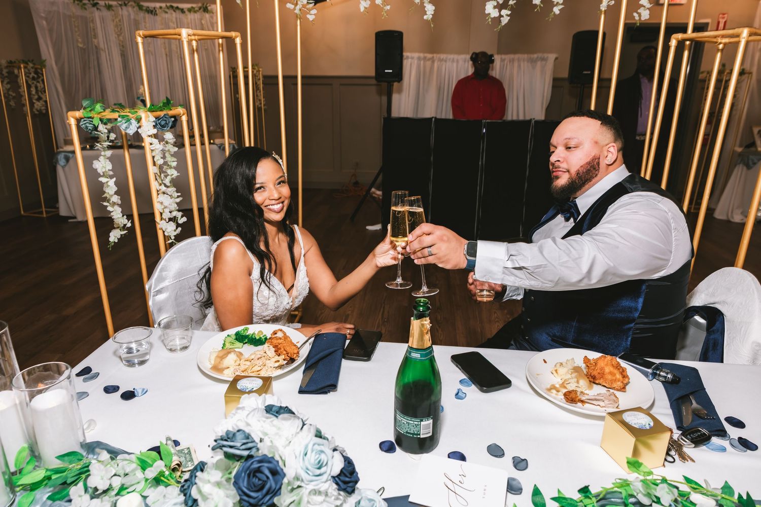 Bride and groom toasting with champagne glasses at wedding reception dinner table with elegant decor.