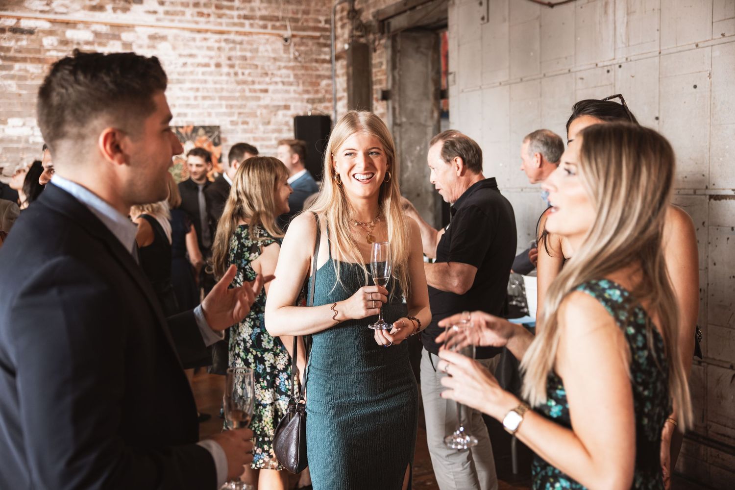 Guests in formal attire laughing and socializing at a stylish indoor wedding reception party.