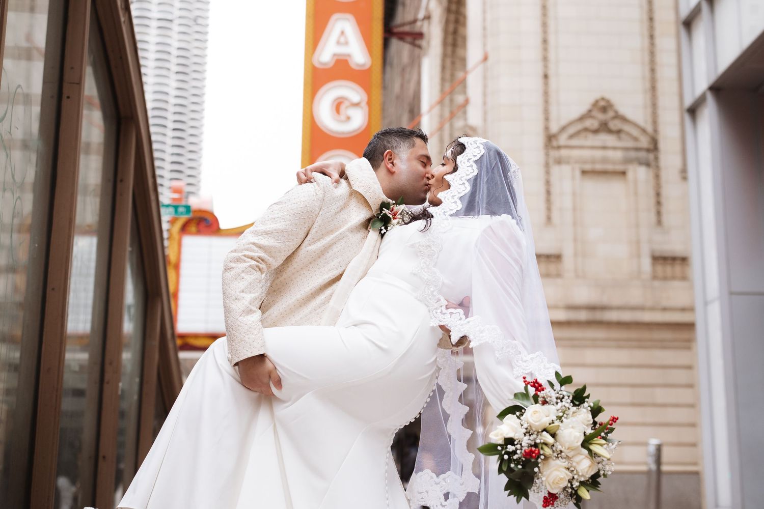 Groom sweeps bride off her feet for a romantic kiss outside a Chicago theater.