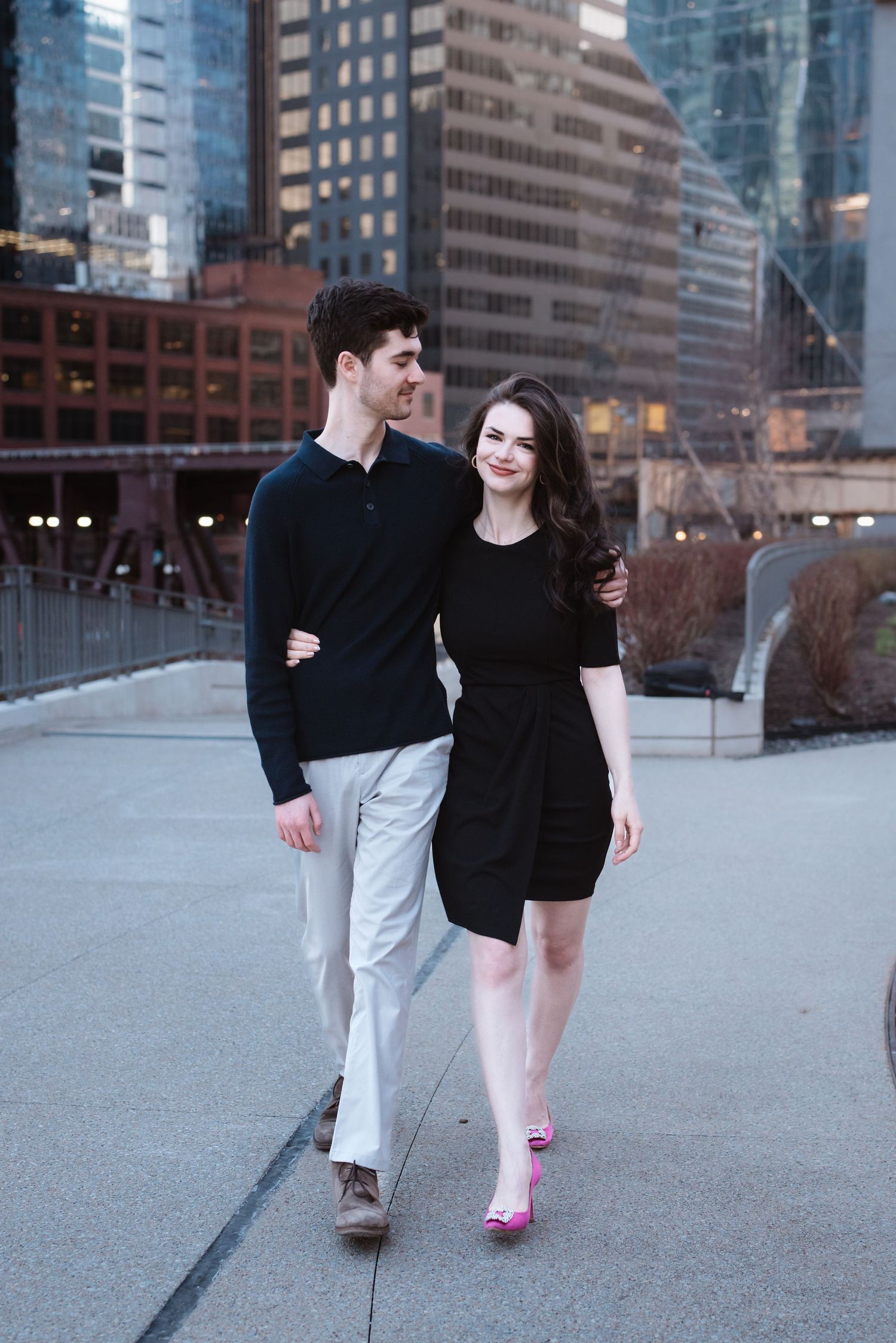 Happy couple walking arm in arm through Chicago city with skyscrapers behind them.