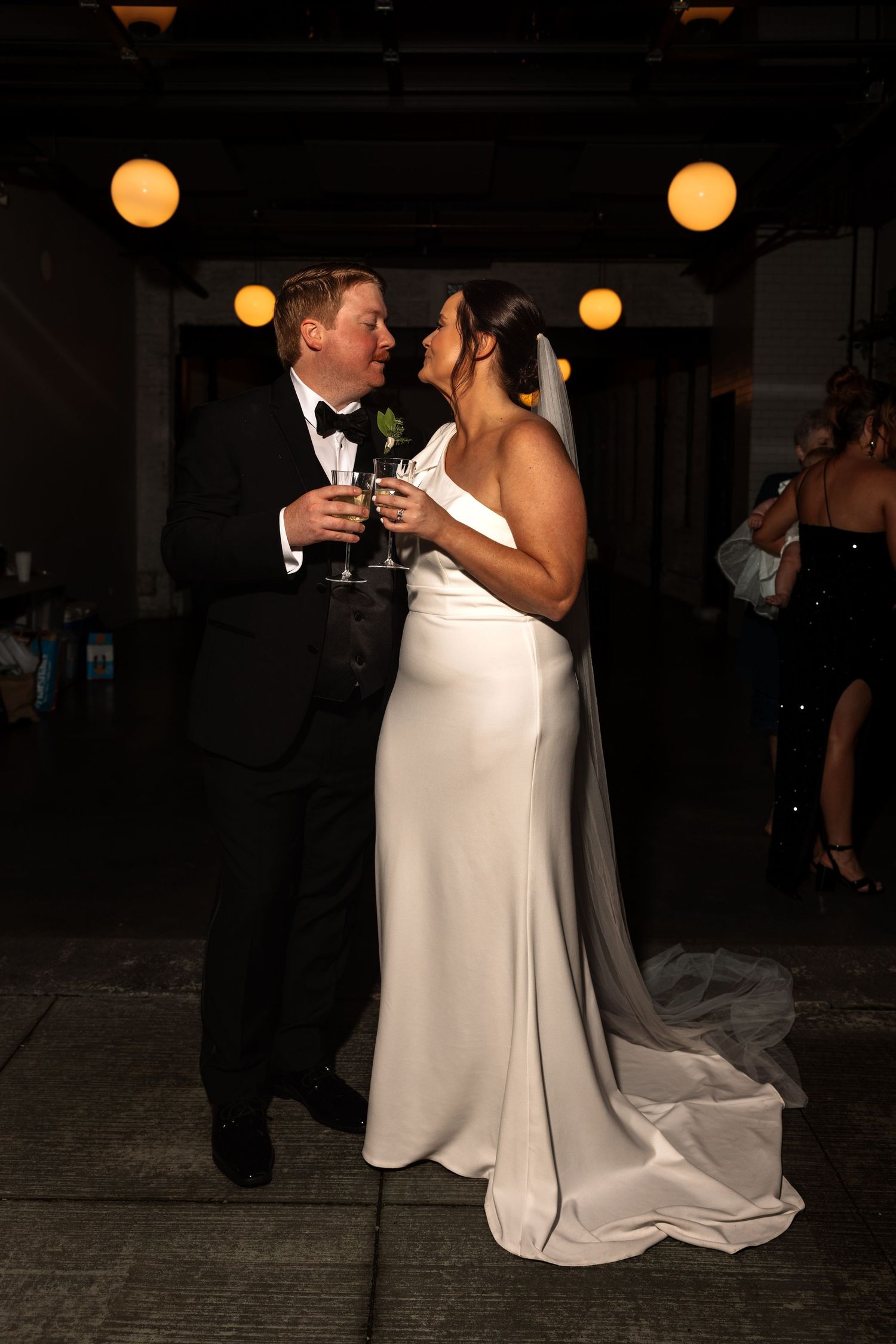 Bride and groom share a romantic kiss while holding champagne flutes at their wedding reception.