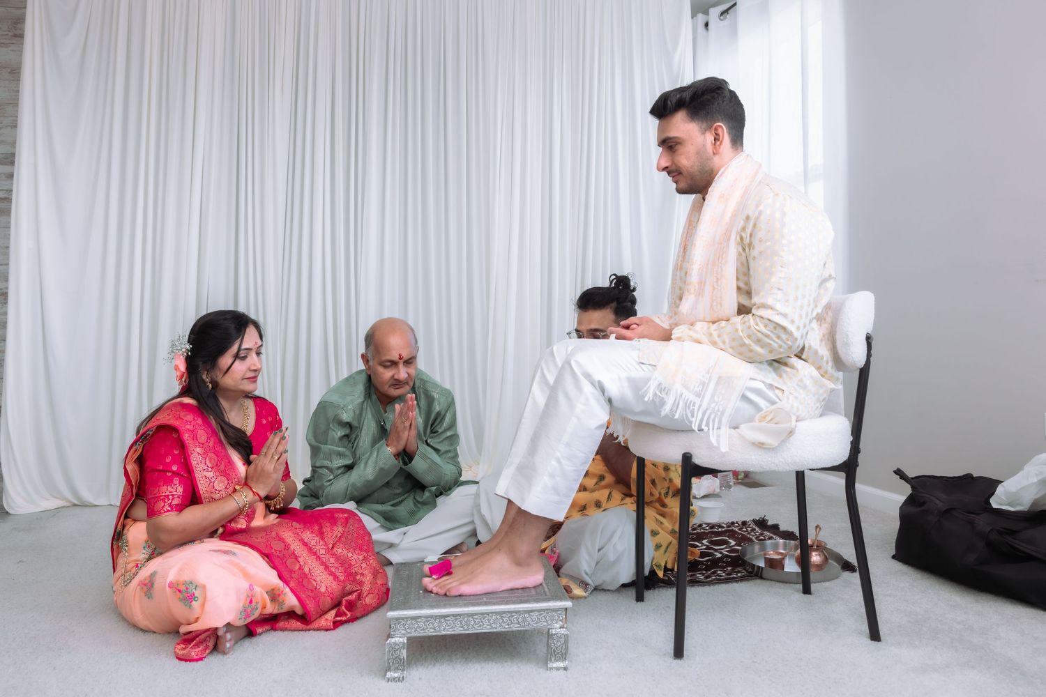 Indian bride and groom perform traditional Hindu wedding ritual with family seated on floor during ceremony.