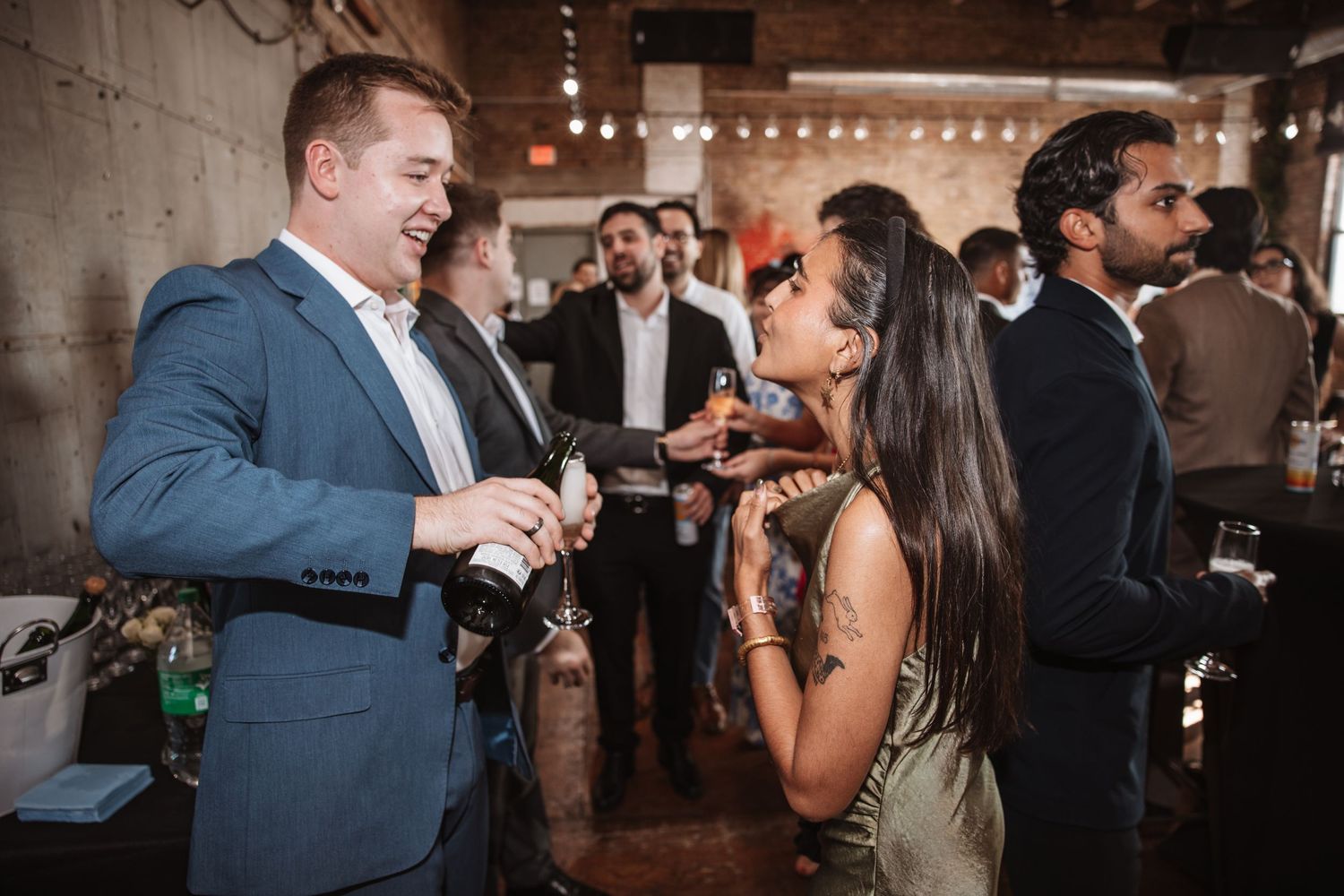 Man in blue suit shares a laugh with a woman at a casual indoor social event.