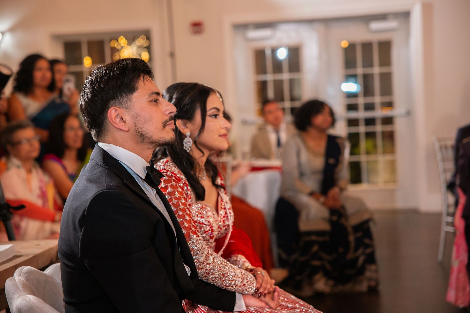 Couple in formal South Asian wedding attire seated together at reception.
