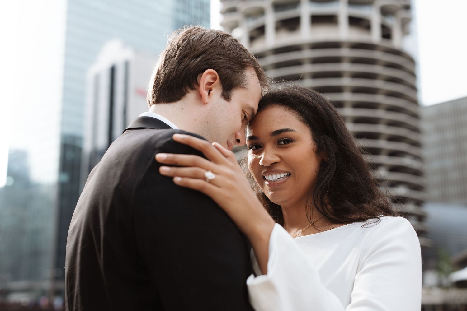 Interracial couple sharing a tender forehead touch while smiling in front of Chicago city skyline.