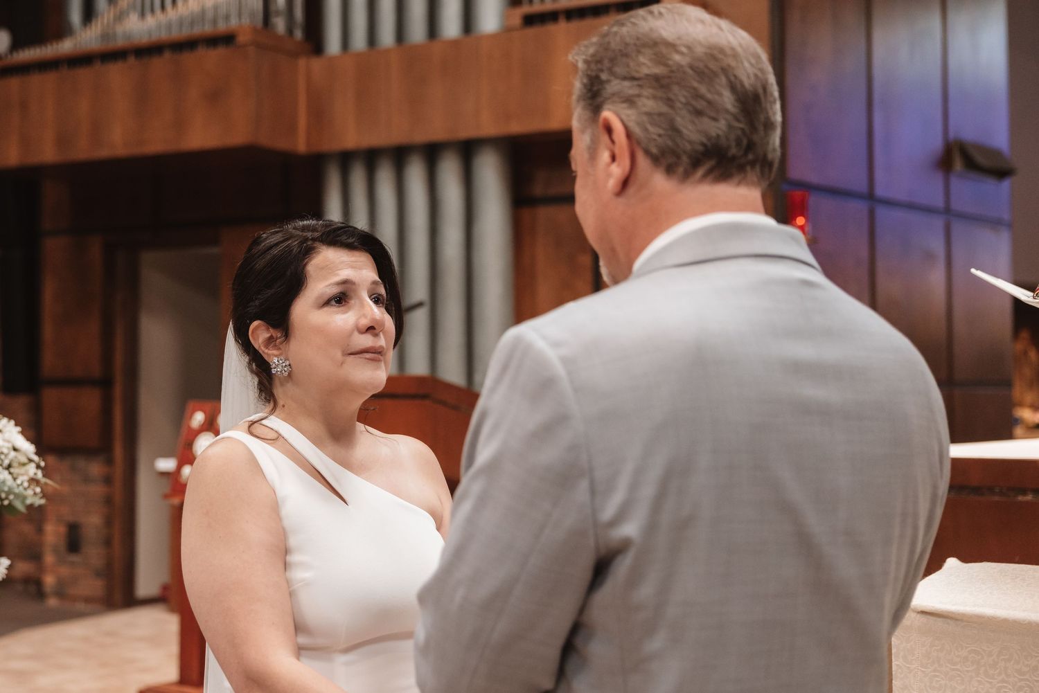 Bride and groom exchange vows facing each other during a wedding ceremony in a church.