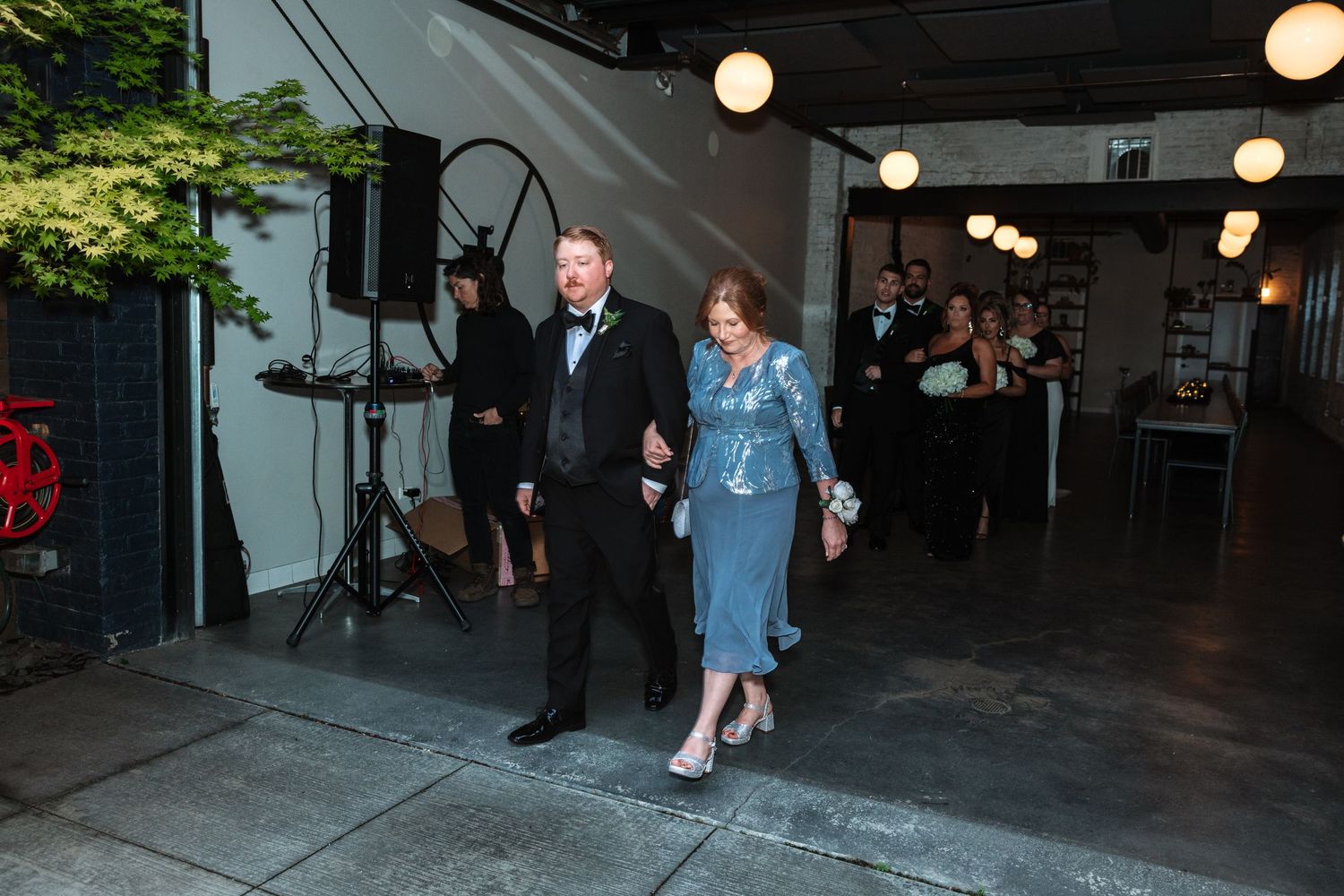 Couple in formal attire walking through wedding venue corridor during reception entrance.