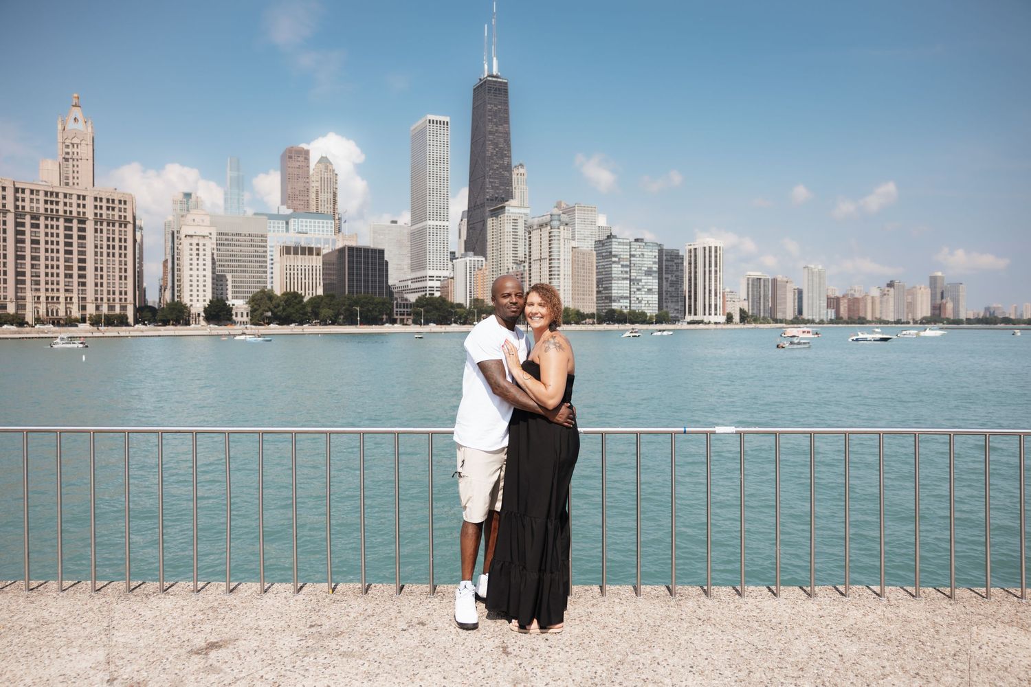 Couple posing romantically with the iconic Chicago skyline and blue lake waters stretching behind them outdoors.