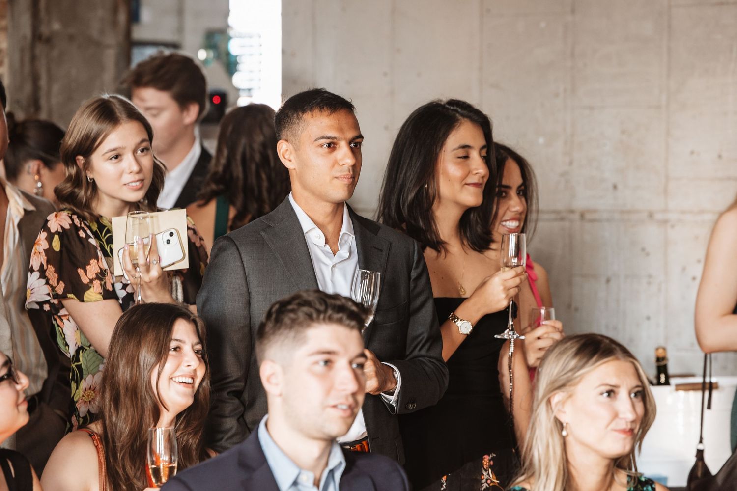 Elegantly dressed guests holding champagne glasses at an upscale indoor social event or wedding reception.