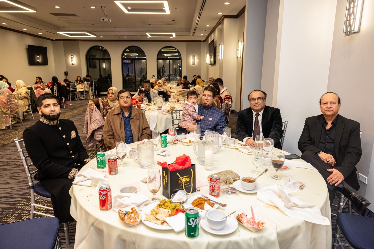Group of guests seated at a round banquet table during a formal dinner event.