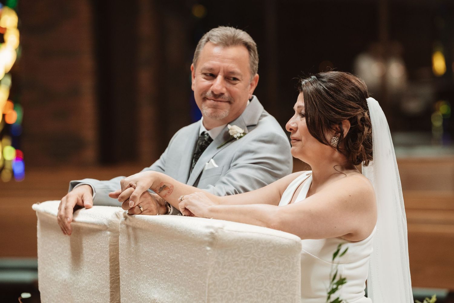 Bride and groom smiling together at the altar during their wedding ceremony inside a church.