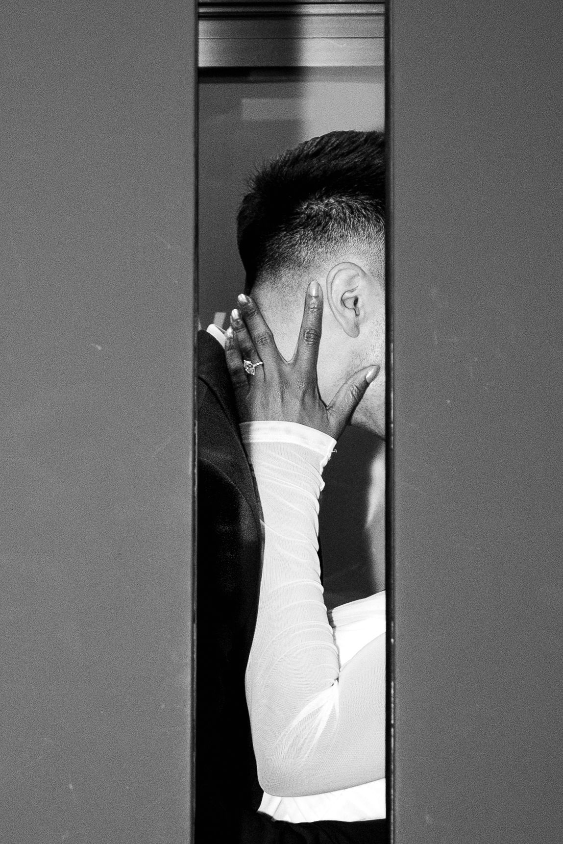 Groom covering his face with his hand in a doorway in a black and white wedding photo.Chicago Wedding Photographer