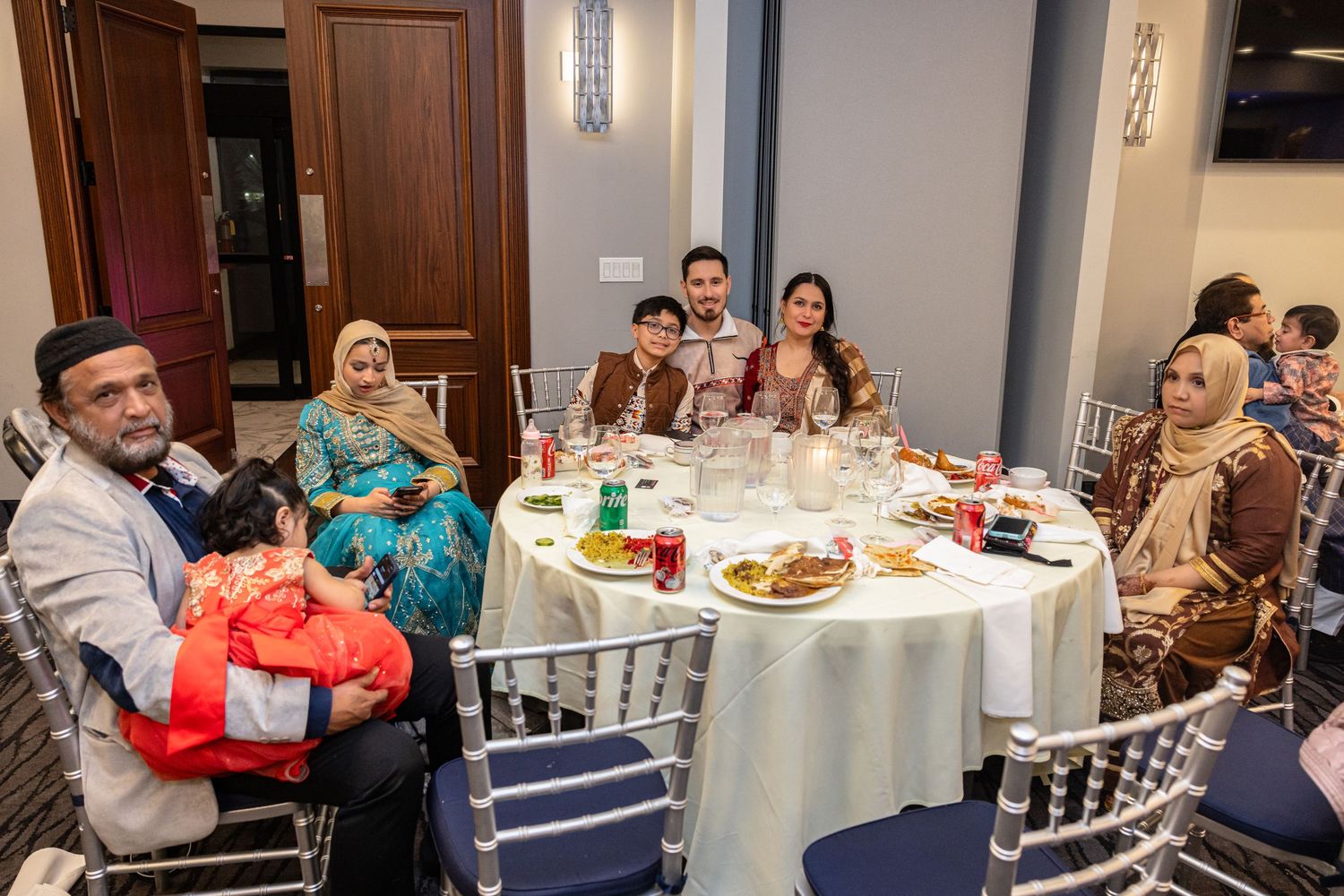 Family group seated at a round banquet table sharing a meal at a formal indoor celebration event.