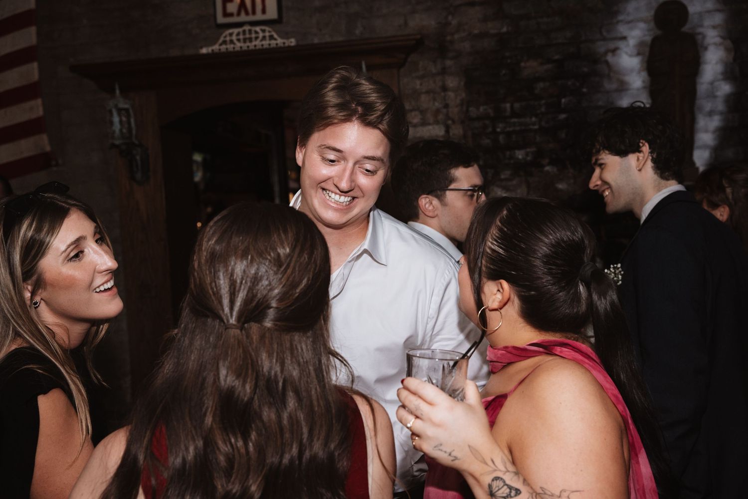 A smiling guest in a blue shirt socializes with friends at an indoor wedding reception party.