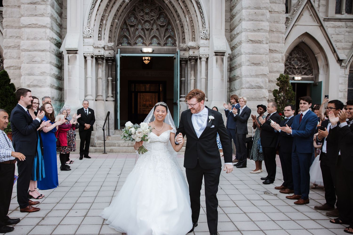 Newlyweds exit grand Gothic church as guests celebrate their wedding ceremony.