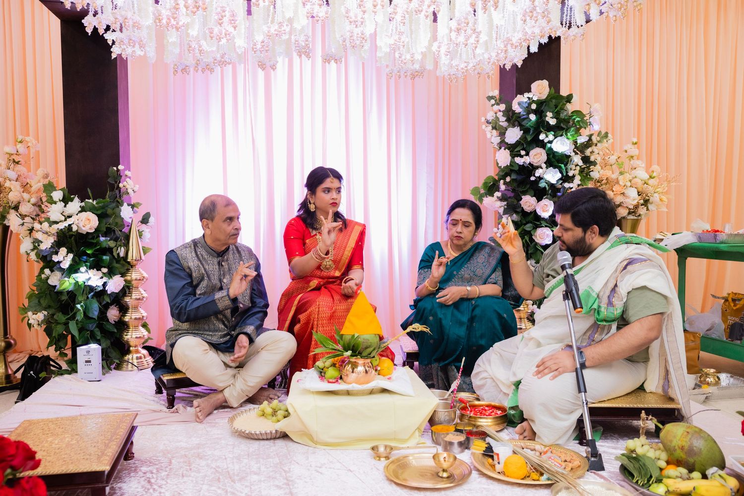 Indian family seated during traditional Hindu puja ceremony with floral decorations and ritual offerings.