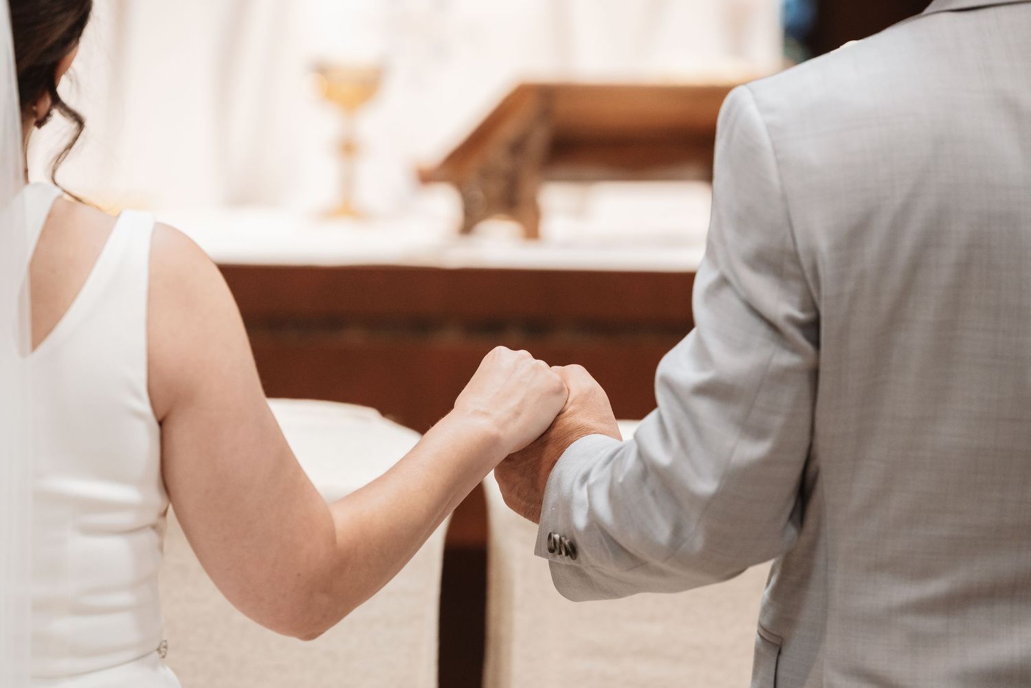 Bride and groom holding hands at church altar during wedding ceremony.