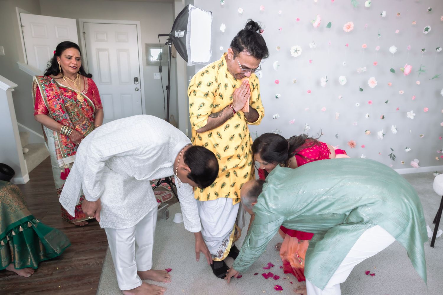 Indian wedding ritual with family members bowing in respect during a traditional Hindu ceremony indoors.