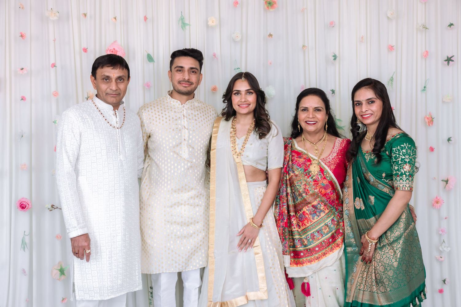 Five guests posing at Indian engagement party in vibrant traditional South Asian attire.
