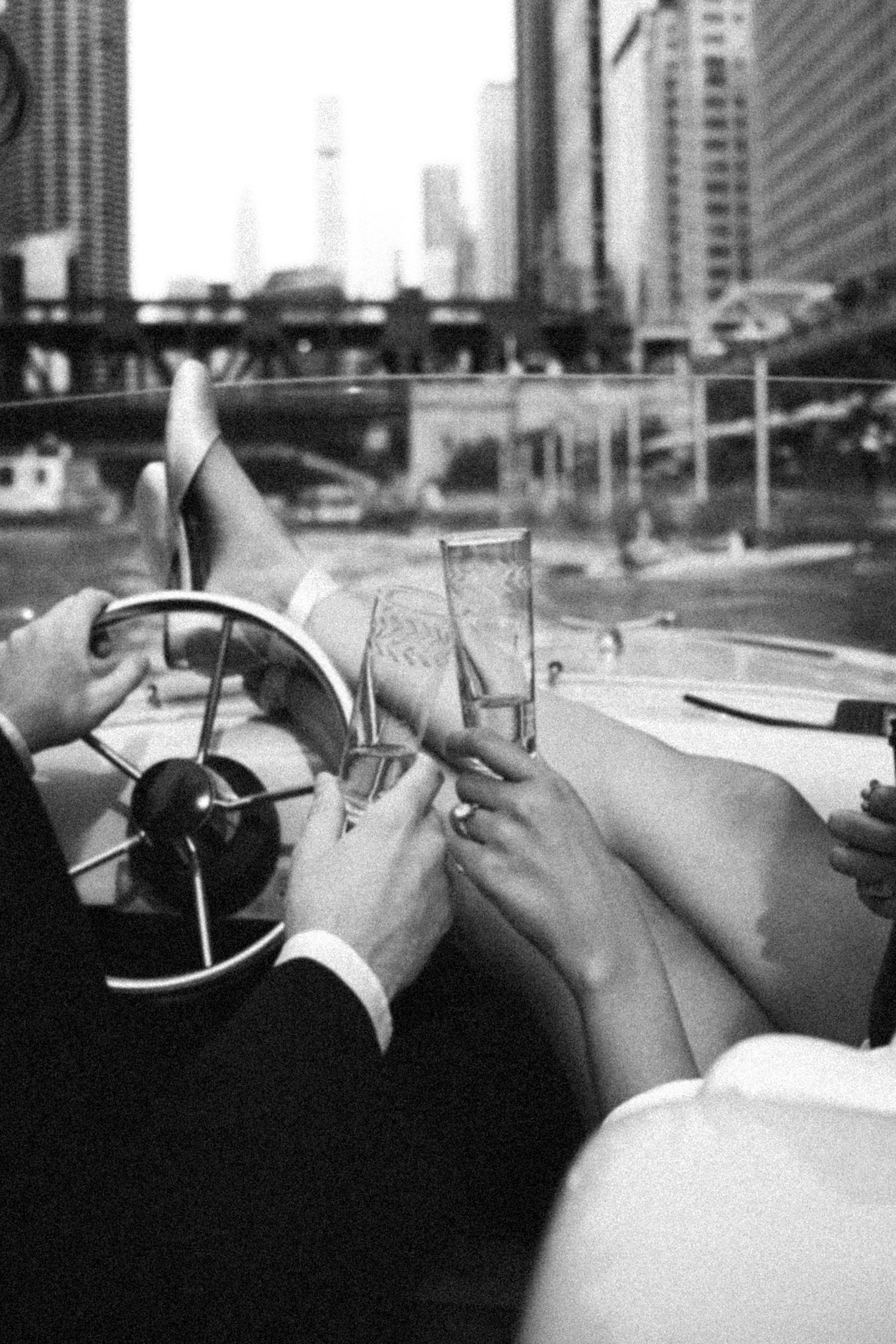 Couple toasting champagne on a luxury speedboat with city skyline in background.