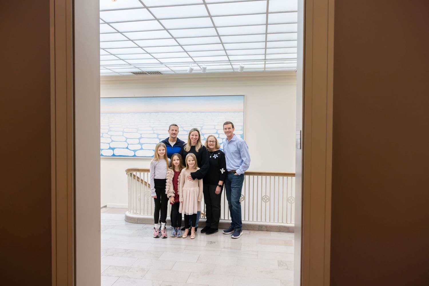 Family group portrait photographed through a doorway in a bright museum atrium.