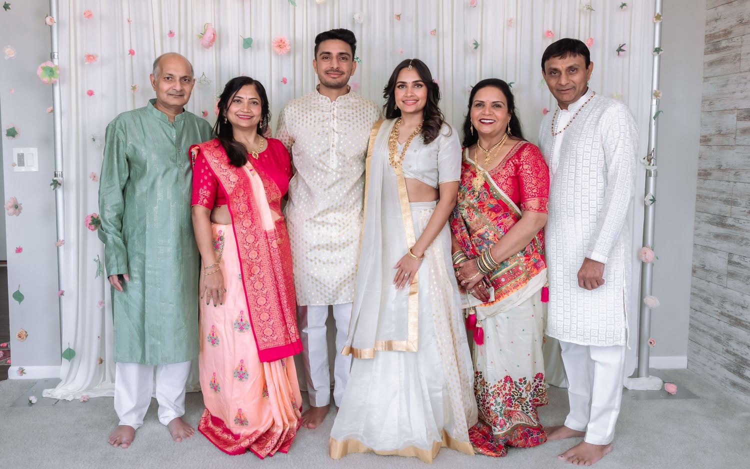 Family of six posing together at Indian engagement ceremony in traditional colorful attire.