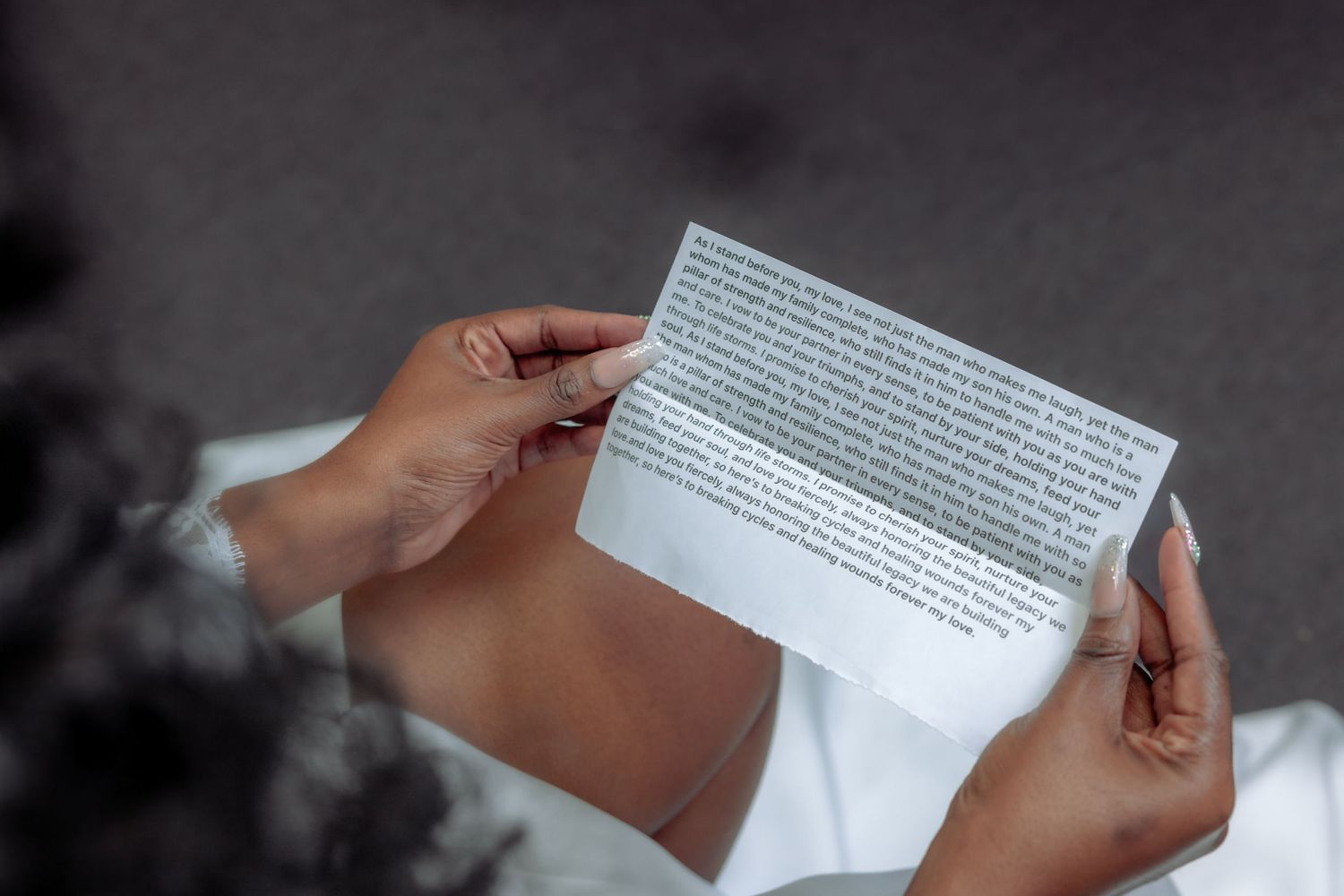 Person in white dress reading a handwritten letter held in both hands.