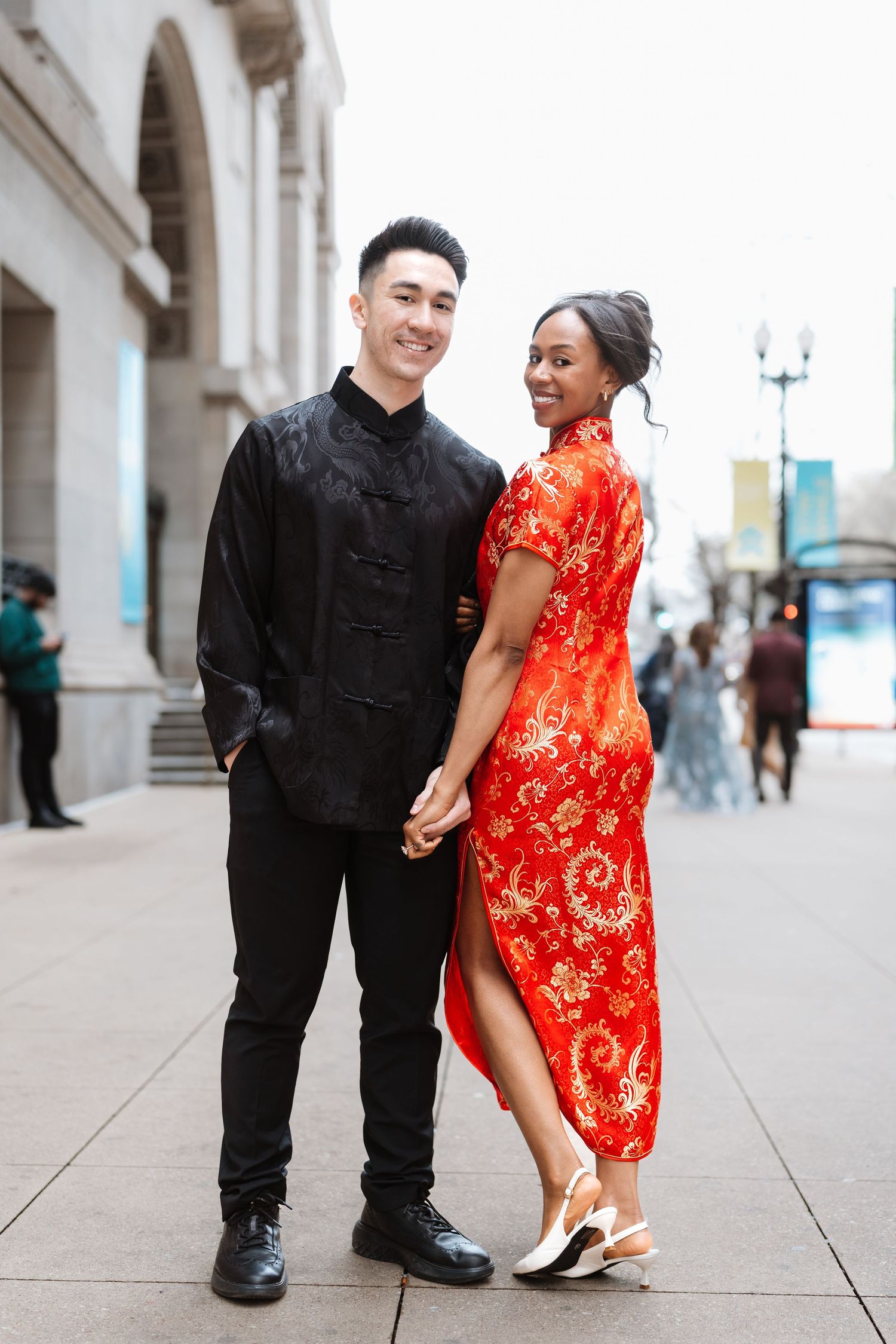 Happy interracial couple in traditional Chinese outfits holding hands and posing on urban sidewalk.
Chicago Wedding Photographer