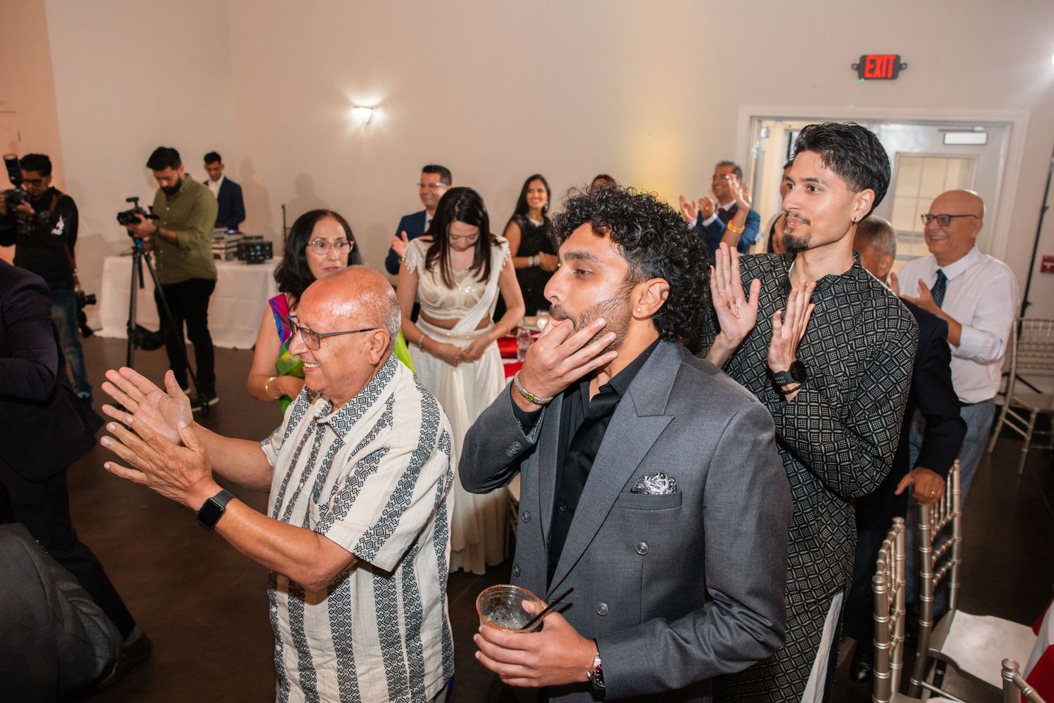 Guests clap and celebrate at elegant Indian wedding reception party on dance floor.