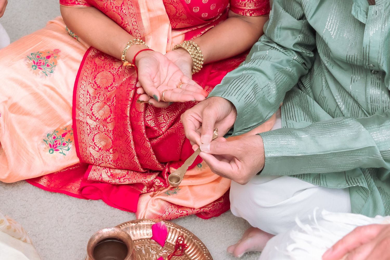 Indian couple performing traditional wedding ritual with colorful silk garments and ceremonial items.