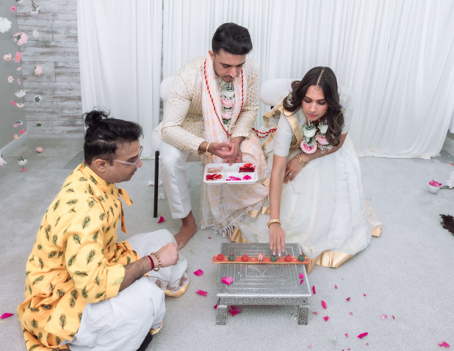 Bride and groom participate in a traditional Indian water ritual ceremony with a priest.