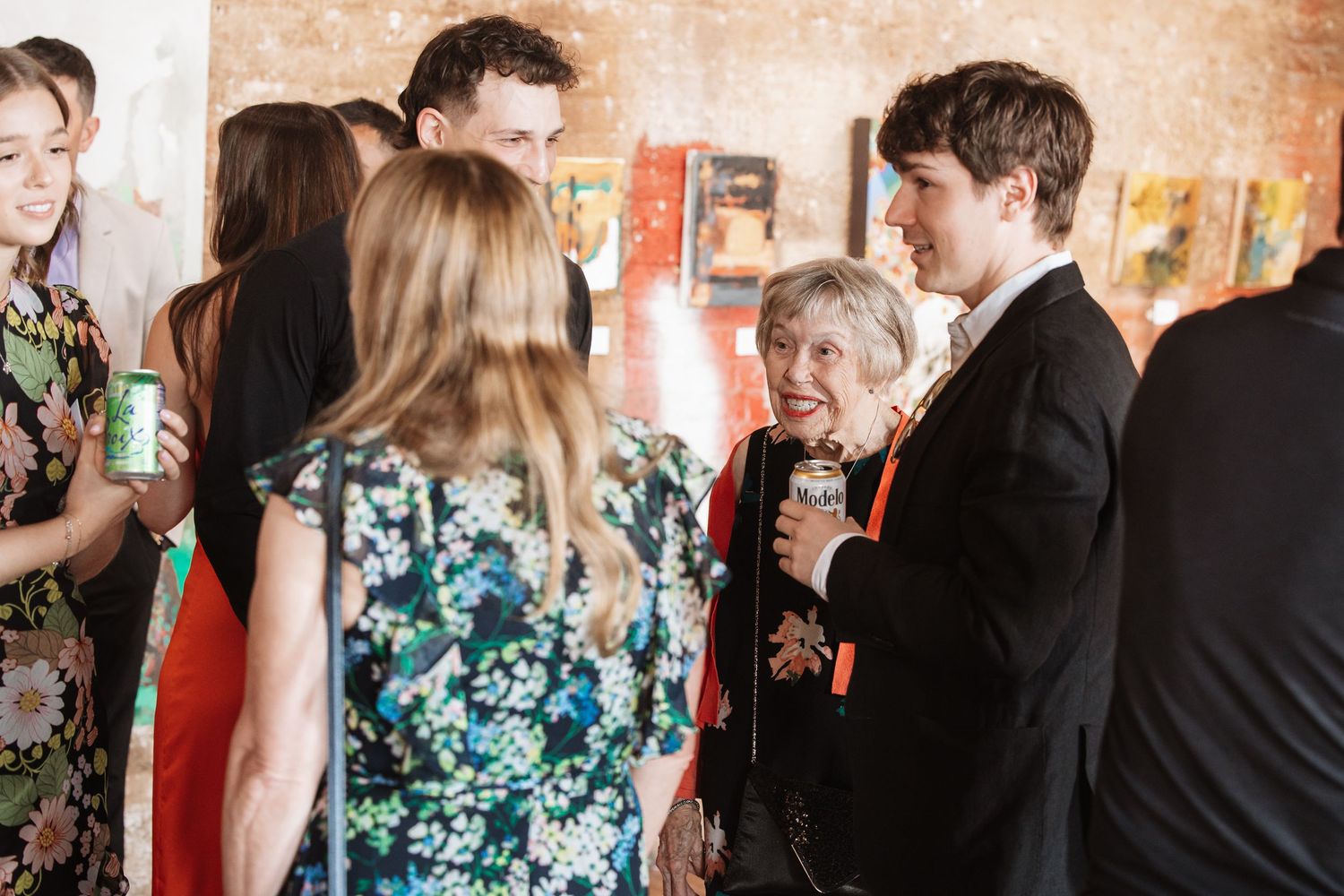 Guests in formal attire conversing near colorful artwork at an indoor gallery event.