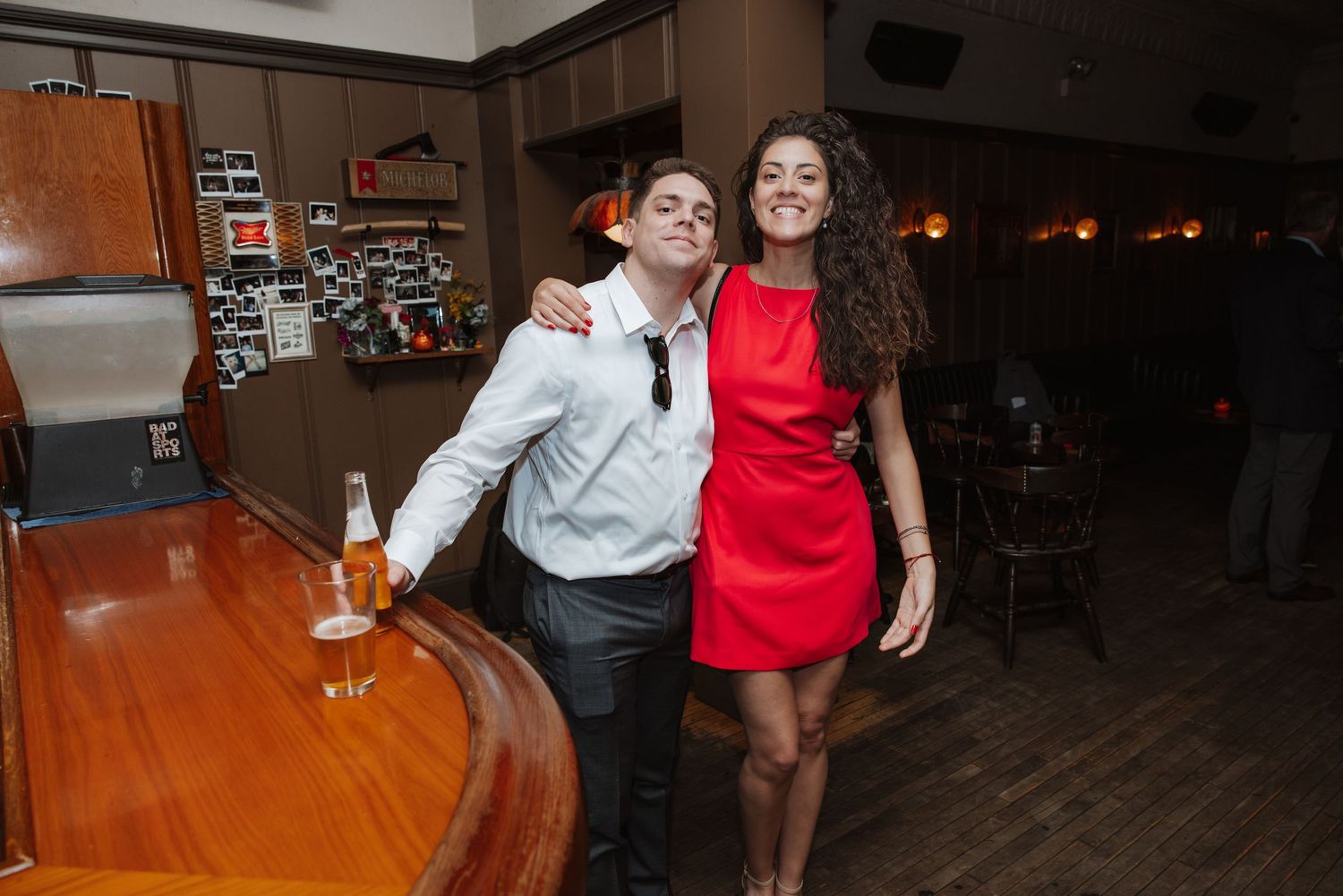 Young couple posing together at a bar during a wedding reception celebration.
