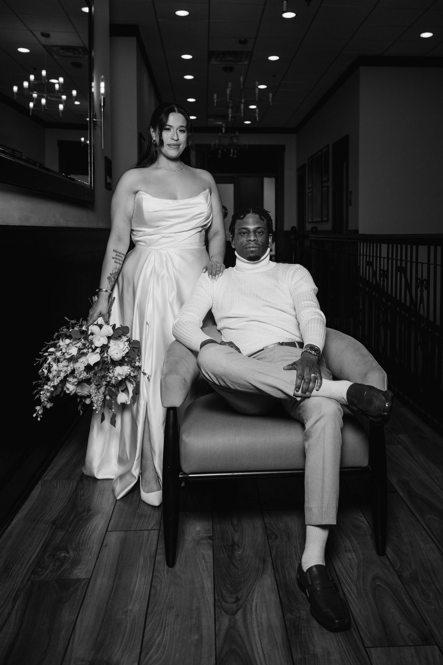 Black and white photo of bride and groom posing elegantly in wedding venue.