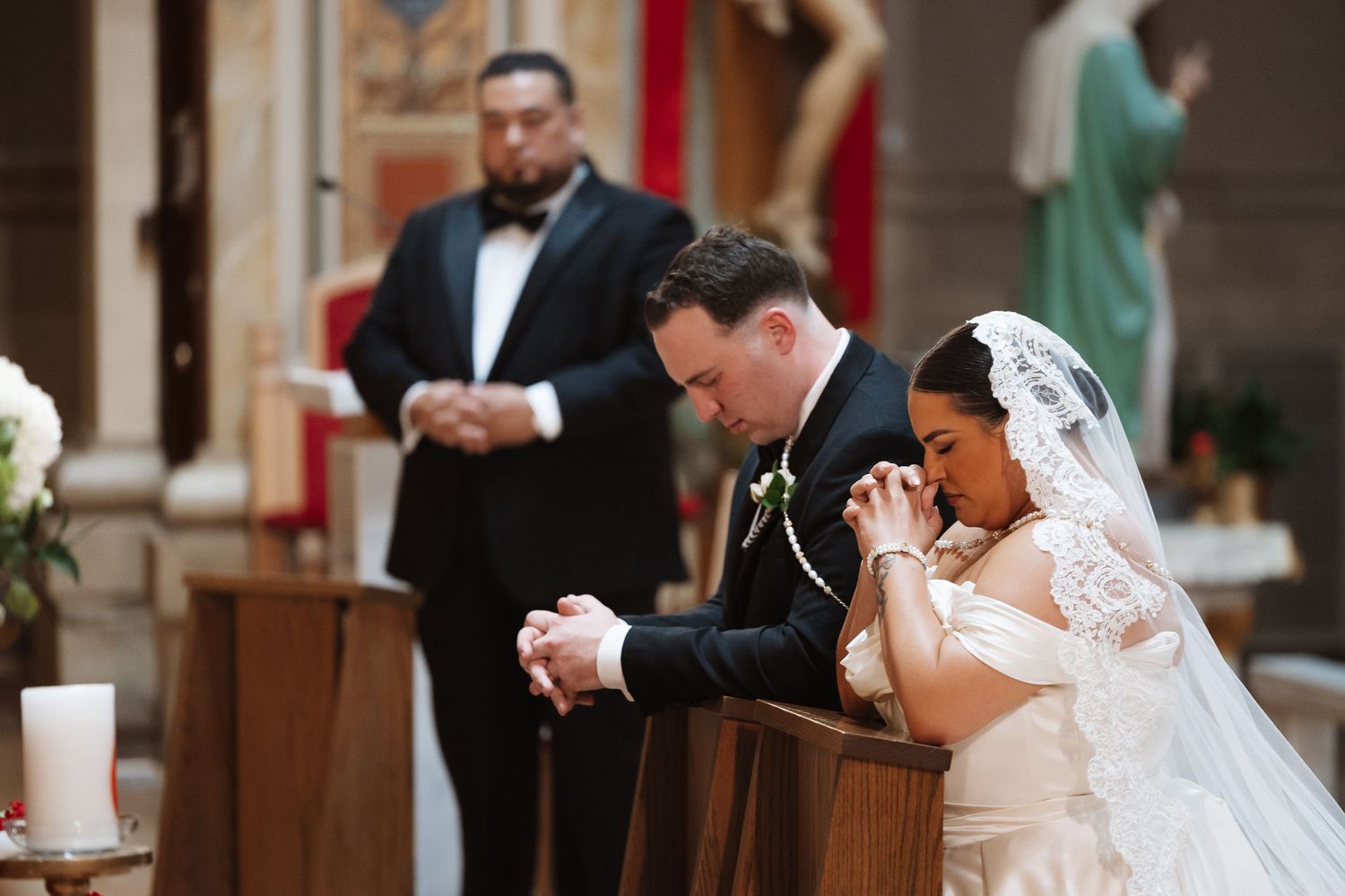 Bride and groom praying together at church altar during Catholic wedding ceremony.