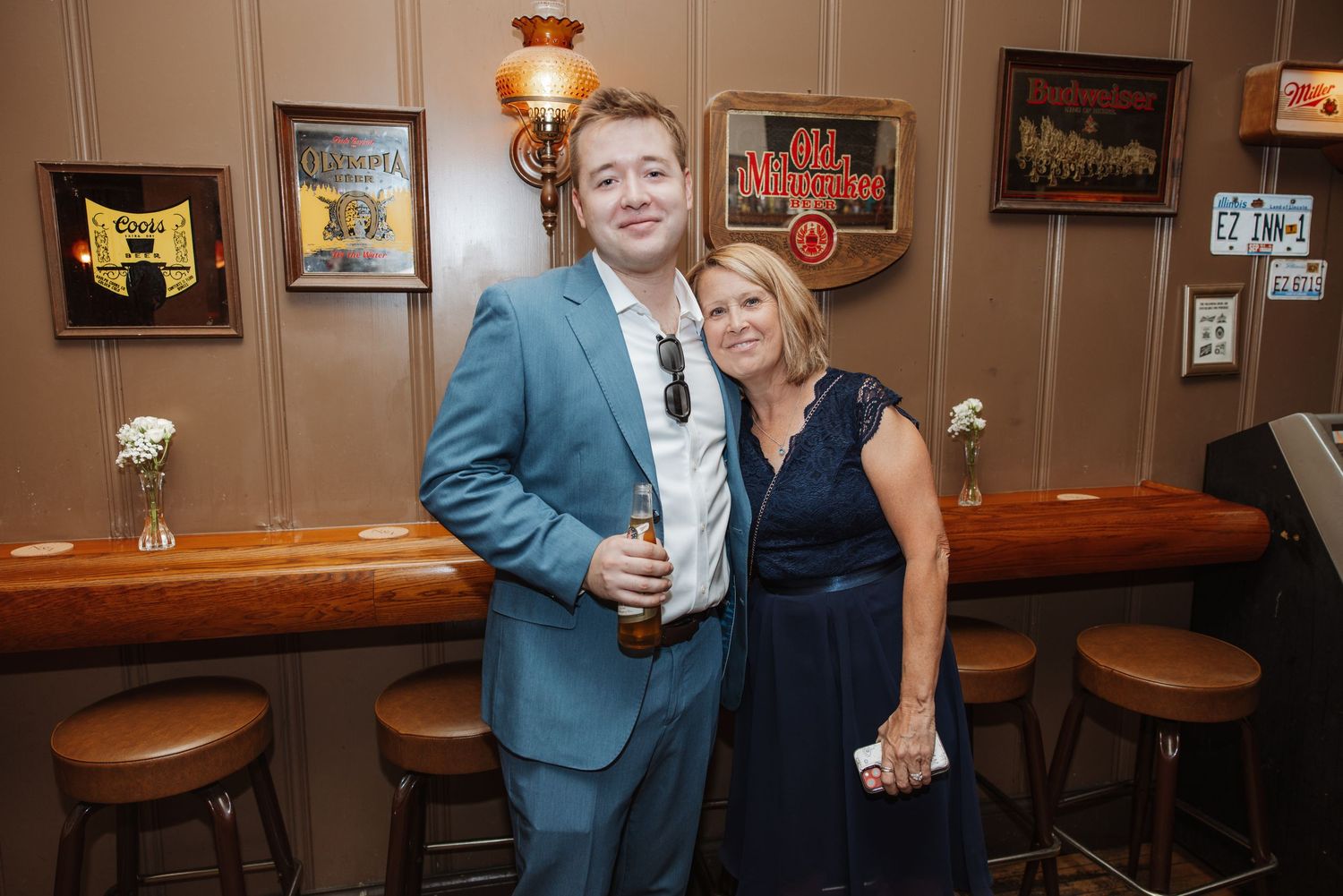Man in blue suit and woman in navy dress posing together at a bar.