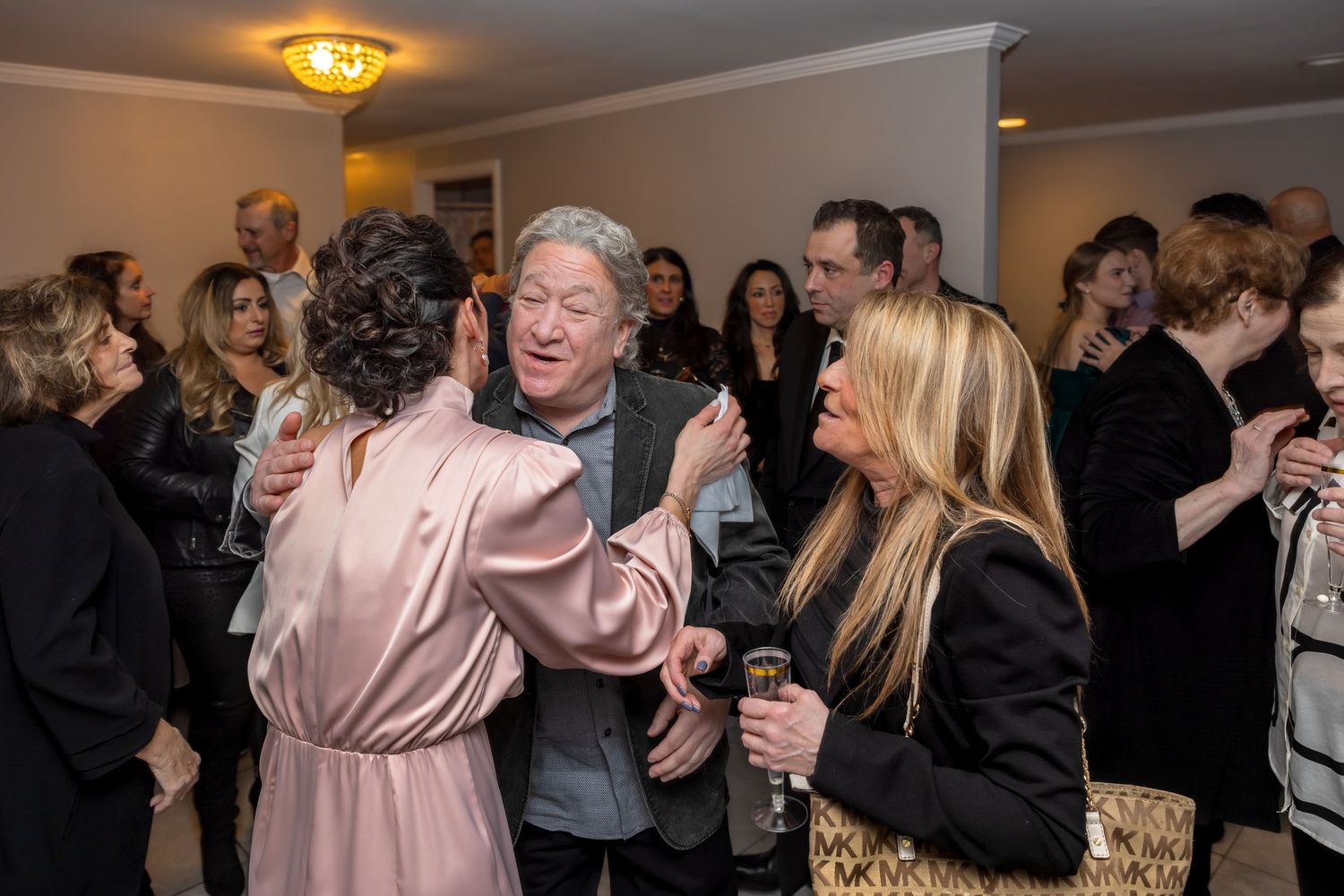 Guests mingling and dancing in pink and black attire at a lively wedding reception.