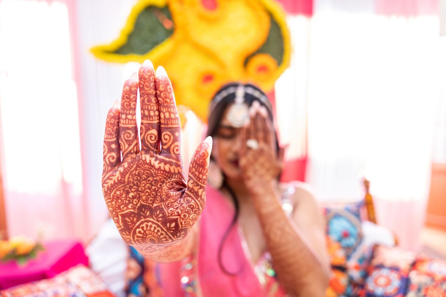 Close-up of intricate bridal mehndi henna design on palm extended toward camera at Indian wedding celebration.