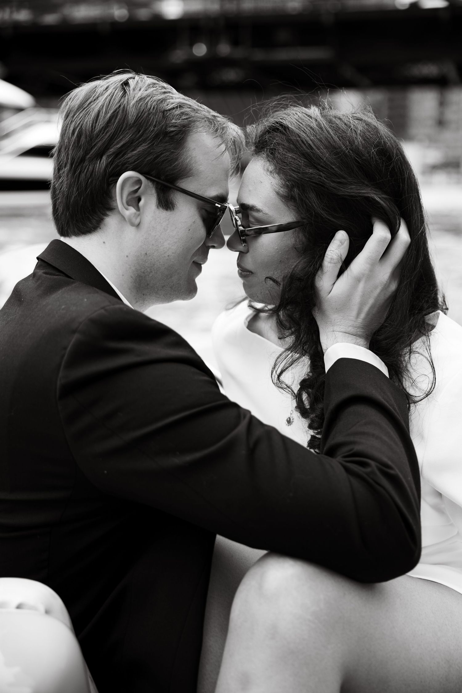 Intimate black and white close-up of couple leaning in for a kiss near a marina.
